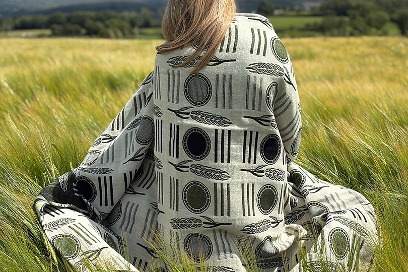 girl sitting in a field with the cae atgofion blanket