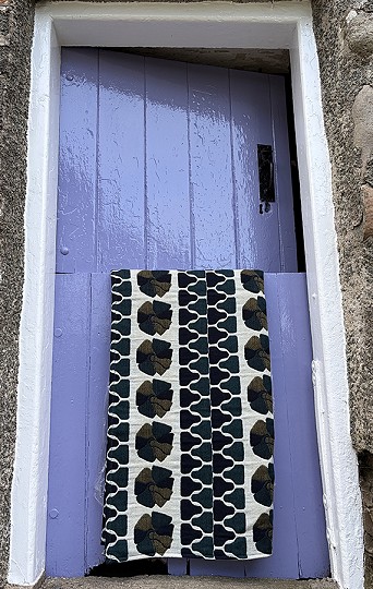 Teal, navy, black and dark yellow blanket over a stable door