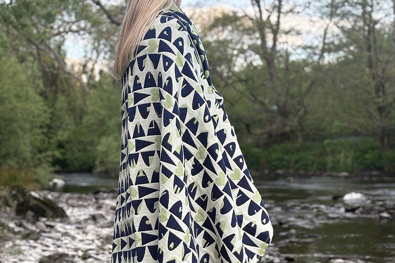 girl with blanket over her shoulders by water