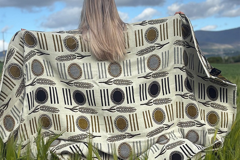 girl holding a large blanket up in a field