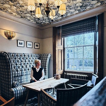 woman sitting on a sofa next to a large window